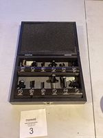 Top view of open black case showing 12 assorted router bits secured in foam insert.