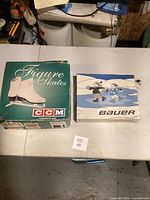 Photo of original green and white CCM figure skates box and blue/white Bauer blade guard bag