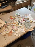 Lot of assorted vintage postage stamps attached to torn pieces of envelope and paper, spread out on a table showing various stamps and fragments.