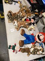 Overview of assorted stuffed animals including Mario, dog, tiger, leopard, and elf plush toys on a table
