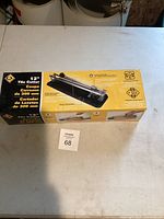 Top-down photo showing the original box packaging of the tile cutter on a white table, including visible product name, dimensions, and some product features.