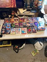 Top-down image showing 24 VHS tapes laid out on a white table, including animation and movie titles.