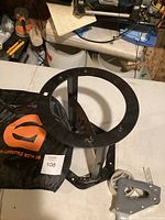 Metal manual wood splitter with circular base, central splitting wedge, and visible mounting holes on the base plate.