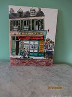Front view of framed oil painting showing the Cafe-Tabac storefront scene against a green background.