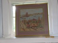 Full framed tapestry on white window shelf showing entire artwork and frame.