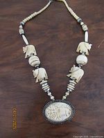 Full view of the necklace showing hand carved elephant beads and central oval carved pendant with elephant design.