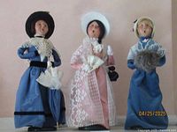 Three Victorian adult female caroler figurines grouped together showing front view.