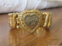 Front view focusing on the heart-shaped centerpiece of the gold-tone expansion bracelet inscribed with "Mother '37".