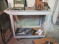 Overall view of metal utility cart with various tools inside including Black & Decker jig saw kit and leather tool belt