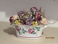 Front view of the white ceramic vase with pink rose floral pattern and artificial flowers inside.