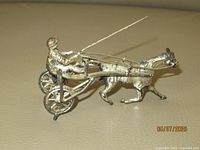 Miniature horse and sulky figurine showing metal craftsmanship, jockey, horse and sulky with wheels and rein details.