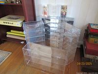 Seven clear acrylic collector display cases of various sizes arranged together. Cases designed for wall mounting with hinged openings.