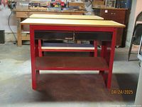 Front view of Craftsman red metal workbench with wood top, two drawers, and lower shelf.