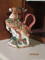 Front and side view of the Fitz & Floyd reindeer figurine showing detailed paint, ribbons, holly leaves, pine cones, and antlers.