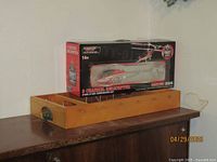 Boxed 3 channel helicopter with gyroscope feature and LED flashing lights sitting on a wooden tray on a surface.