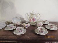 Full tea set including cups, saucers, pitcher, creamer, and sugar bowl arranged on table
