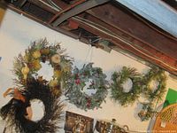 Six holiday wreaths on a wall showing various natural and black twig wreaths with some ribbons.