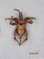 Full frontal shot of the Venetian jester mask showing all six points with gold bells, ornate gold detailing, and red fabric base.