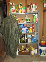 Metal shelving unit filled with pest control products and green rain suit hanging on side
