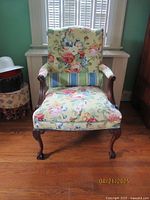 Front view of Queen Anne style chair showing floral upholstery and wood legs