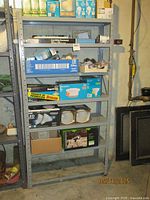 Photo of a metal shelving unit loaded with assorted light bulbs and lighting supplies in a basement setting.