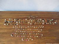 Full view of the jewelry set including the long stone and beaded necklace, the three similar stone necklaces wrapped in wire, and the geometric style beaded necklace and bracelet.