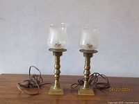 Pair of vintage brass table lamps with frosted glass shades showing full lamps and cords.