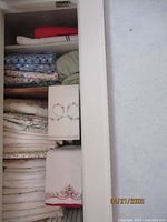 Closet shelves with folded embroidered towels and linens in white and pastel colors.