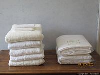 Side view of 6 bath towels with 2 small towels on top, displaying thickness and texture of towels.