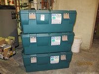 Three stacked green Tucker storage lockers in a basement setting, showing the overall size and condition of the boxes.