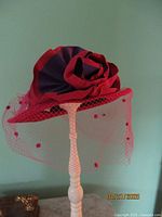 Red wool wide brim hat with rose and red netting on display stand