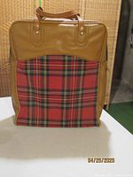 Front view of vintage thermos bag with brown leather-like exterior and plaid fabric front pocket.