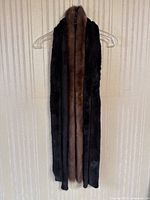 Three thin mink fur scarves hanging side by side on a hanger showing full length and varying fur colors.