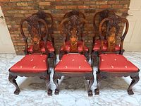 Front view of all six chairs lined up against a brick wall on marble floor.