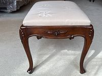 Front view showing carved floral design on wood apron, cabriole legs, and bow pattern upholstery.