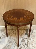 Front view of round side table showing floral inlay and brass rim