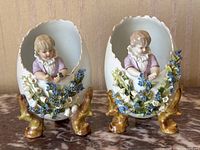 Two porcelain egg figurines side by side on marble surface