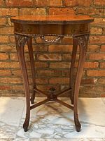 Front view of side table showing scalloped marquetry top, carved edge, brass rim and cabriole legs