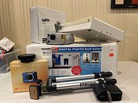 All items arranged on table, showing kit box, lightbox unit, Canon box, cameras, tripod and memory cards