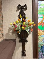 Wall mounted antique carved wood planter with brightly colored artificial tulips for display.
