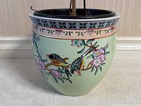Full view of the circular Chinese porcelain jardiniere planter with plant inside and visible hand-painted birds and flowers.