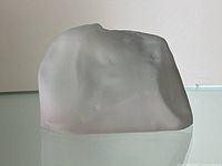 Front and side views of frosted glass rough-shaped Cullinan diamond replica showing matte surface and one visible chip.