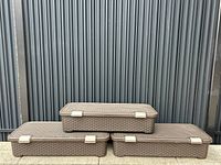 Three dark brown plastic storage bins stacked and arranged to show front side, lids, clips and shape.