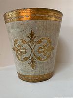 Front view of basket showing central gold scroll motif on beige background