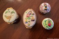 Four boxes arranged on wood surface showing all motifs: bird, pansies, bee, ladybug