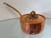 Full view of saucepan with lid and handle on glass surface