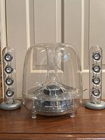 Front view of clear acrylic subwoofer with two satellite speakers