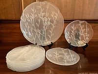 Seven plates stacked with one plate on stand showing full set and pattern.