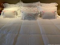 Full bed view showing white king duvet and ten pillow shams