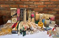 Full view of assorted candles displayed on table against brick wall